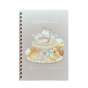Front cover of a spiral notebook on a black background. Sugar Cocomuu, a white bunny character, stands atop a dessert tier with small candy friends surrounded by sweets and bear cookies.
